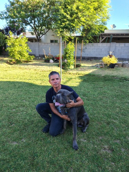 Win kneeling beside a gray dog in a backyard